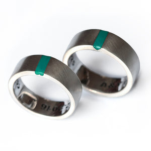 His and hers matching wedding bands in brushed silver with turquoise enamel inlay and hidden heart negative space.
