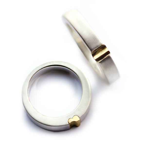 White gold magnetic couple rings, one band shows yellow gold half-heart edge, matching set for wedding or anniversary
