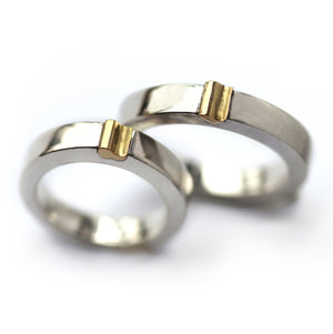 Close-up of matching magnetic wedding bands, white gold with yellow gold connector detail, two-tone couple ring set
