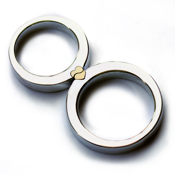 
Magnetic couple rings placed together forming a solid yellow gold heart, two tone wedding bands combining polished white gold with interlocking heart design revealed when the rings connect.