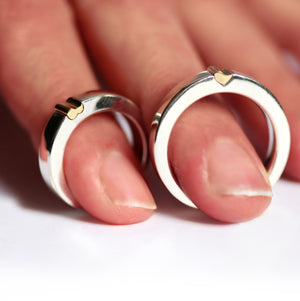 Matching magnetic heart couple rings worn on fingers, showing two tone white gold bands with yellow gold heart tips designed to attract and align before touching.