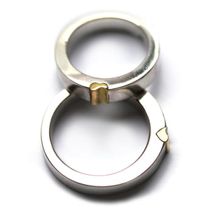 Interlocking magnetic wedding rings displayed vertically, highlighting the yellow gold heart connector and polished white gold bands that form a hidden heart when joined together.