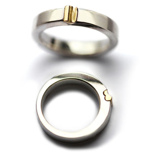 Close-up of magnetic two tone wedding bands showing the raised yellow gold heart clasp containing miniature magnet technology allowing the rings to connect as symbolic relationship rings.