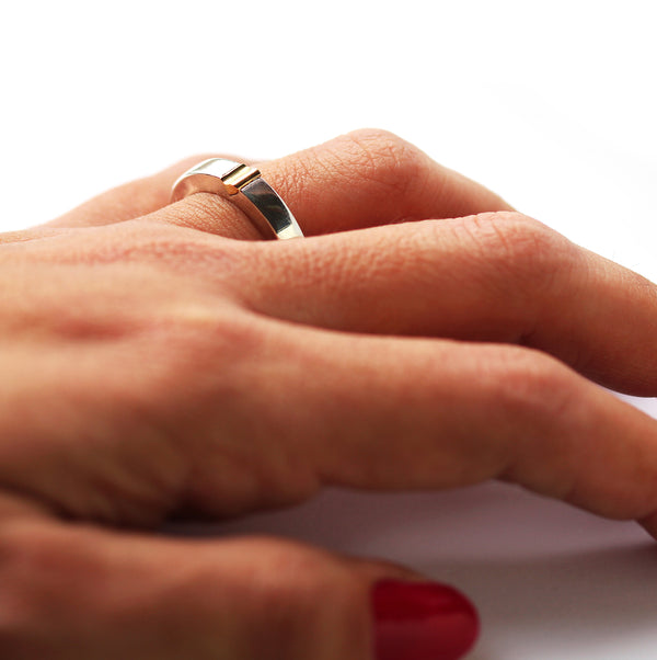 Two tone magnetic wedding band worn on hand featuring polished white gold band with yellow gold heart connector, part of matching interlocking couple rings designed to form one heart together.