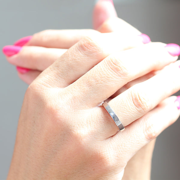 Woman wearing white gold hidden heart ring, minimalist modern wedding band close up on hand