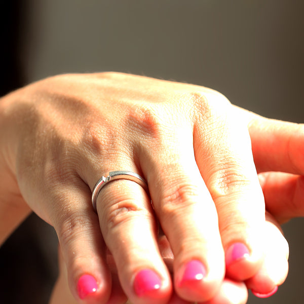 White gold hidden heart engagement ring worn on hand, sleek minimalist promise ring design