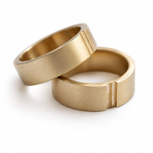 Cadi matching gold wedding bands with a brushed finish and paired groove details, shown overlapping at an angle