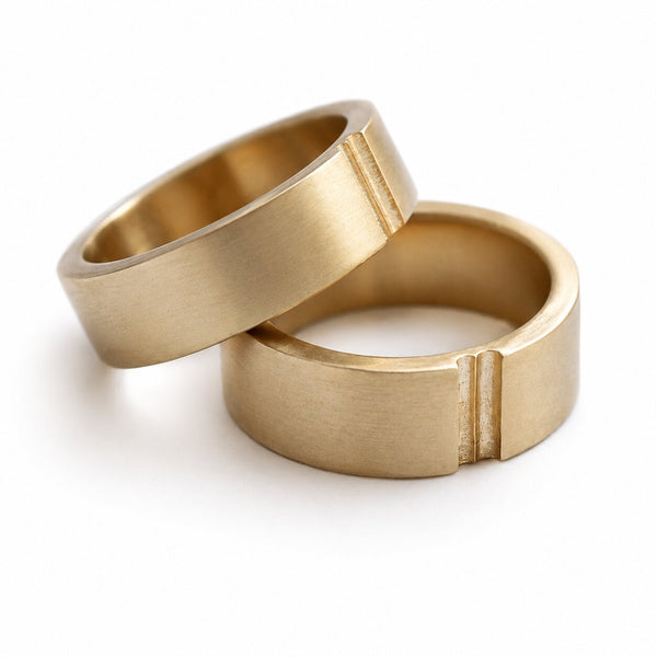Cadi matching gold wedding bands with a brushed finish and paired groove details, shown overlapping at an angle
