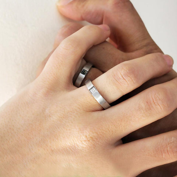 Hands wearing two white gold promise rings for couples with diamonds