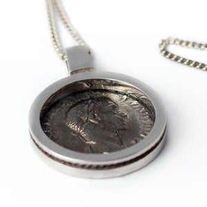 black Roman coin surrounded by a clean and classic design pendent is a replica of a genuine antique Roman coin