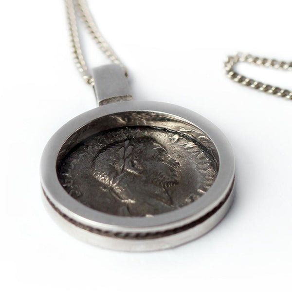 black Roman coin surrounded by a clean and classic design pendent is a replica of a genuine antique Roman coin