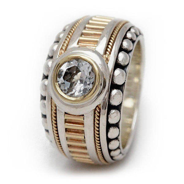Cadi Donut cocktail ring with a bold round clear gemstone set in a sculptural band, detailed with gold accents and silver beading.