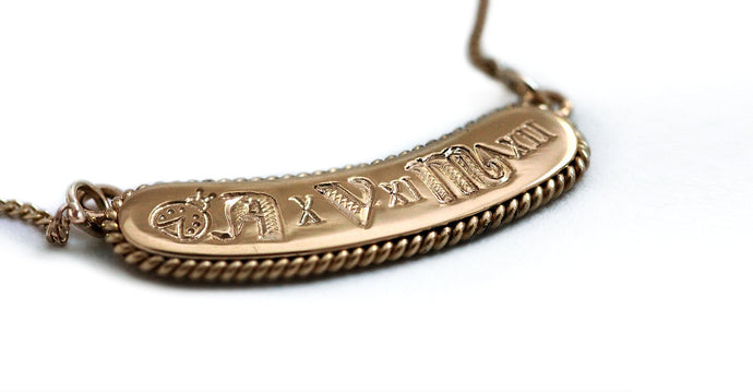 A hand-fabricated design with a unique personal statement in a geometric font shaped a filigree decoration in 18k gold, a Name bar necklace